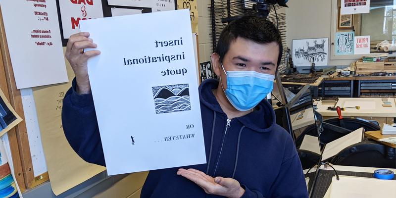 Benjamin Ng graphic design student at Bemidji State holding up a letterpress print